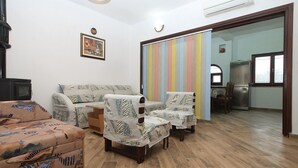 A living room with a sofa, armchairs, a small table, and a cabinet. There is a refrigerator and a window in the background. - Apartment 1775 (Medulin)