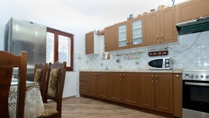 A kitchen with wooden cabinets, a microwave, an oven, and a dining table with chairs. - Apartment 1775 (Medulin)