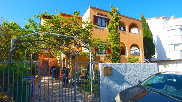 A gated entrance with a stone pathway leading to a building with arched windows and a tiled wall. - Apartment 1775 (Medulin)
