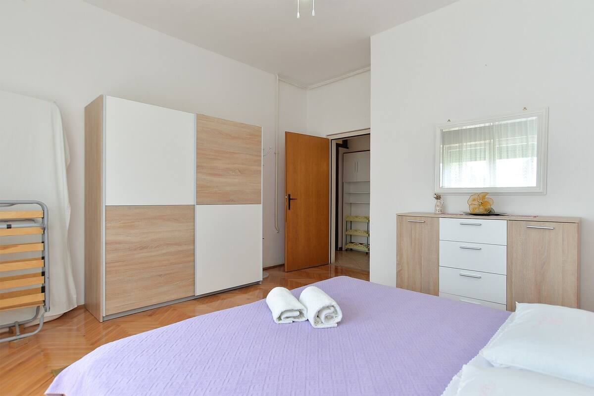 Une chambre à coucher avec un lit, une armoire, une table de chevet et une fenêtre.