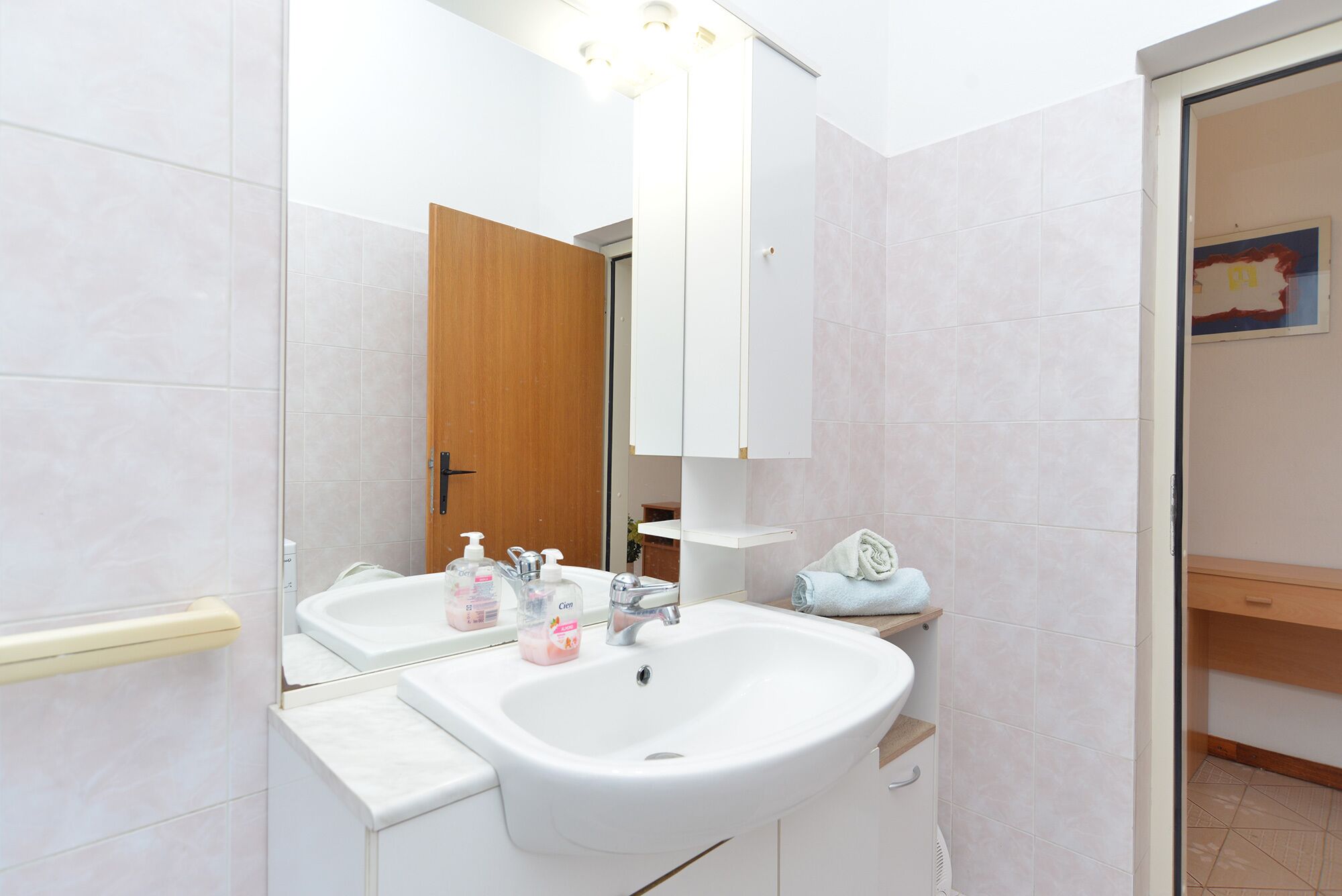 A bathroom with a white sink, a mirror, and a wooden door.