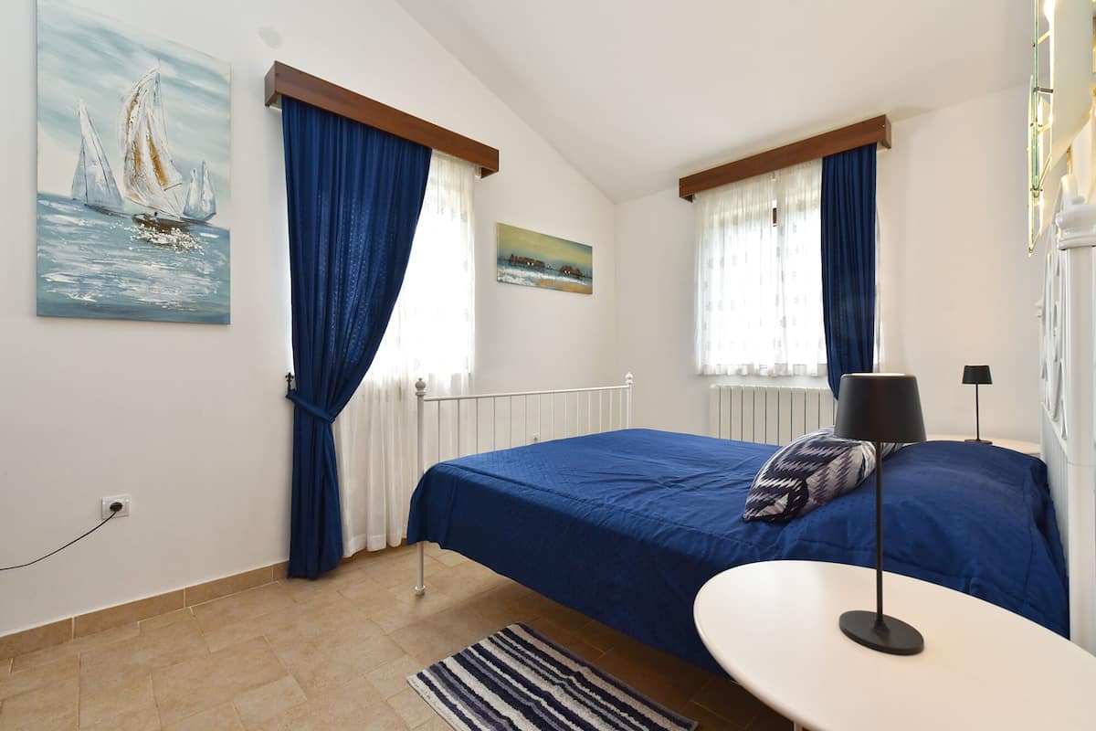 Ein Schlafzimmer mit zwei Betten, einem Heizkörper, einem Gemälde mit Segelbooten und einem kleinen Tisch mit einer Lampe.