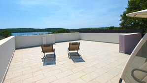 A rooftop terrace with two chairs and a table, overlooking a lake and hills. - House 1790 (Medulin)