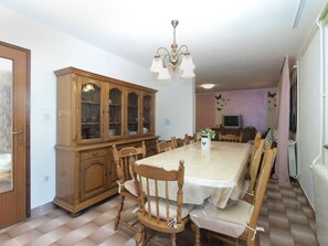 A dining room with a large wooden cabinet, a chandelier, and a table set for six.