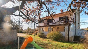 A house with a stone wall, a green slide, and a brick pathway. - Apartment 1794 (Liznjan)