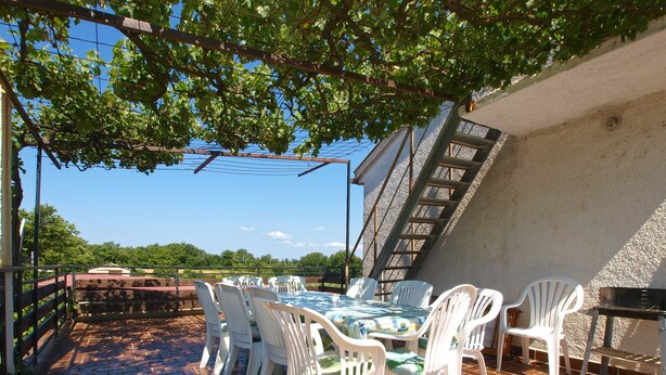 An outdoor patio with a table and chairs, a brick floor, and a staircase leading to an upper level. - Apartment 1794 (Liznjan)