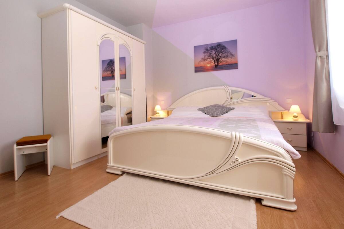 Une chambre à coucher comprenant un lit, des tables de chevet, une armoire et une petite table.