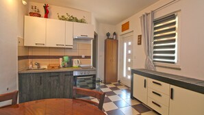Una cocina compacta con una mesa de comedor, horno empotrado y cafetera.