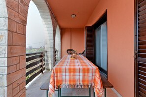 A balcony with a checkered tablecloth, a wooden bench, and a view through a window with blinds. - Apartment 1803 (Vodnjan)