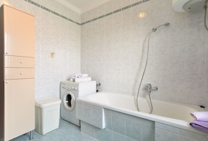 Ein Badezimmer mit Waschmaschine, Badewanne und Schrank.