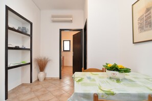Ein Essbereich mit einem für zwei Personen gedecktem Tisch, einer Vase mit Trockenpflanzen und einer Wand-Klimaanlage.