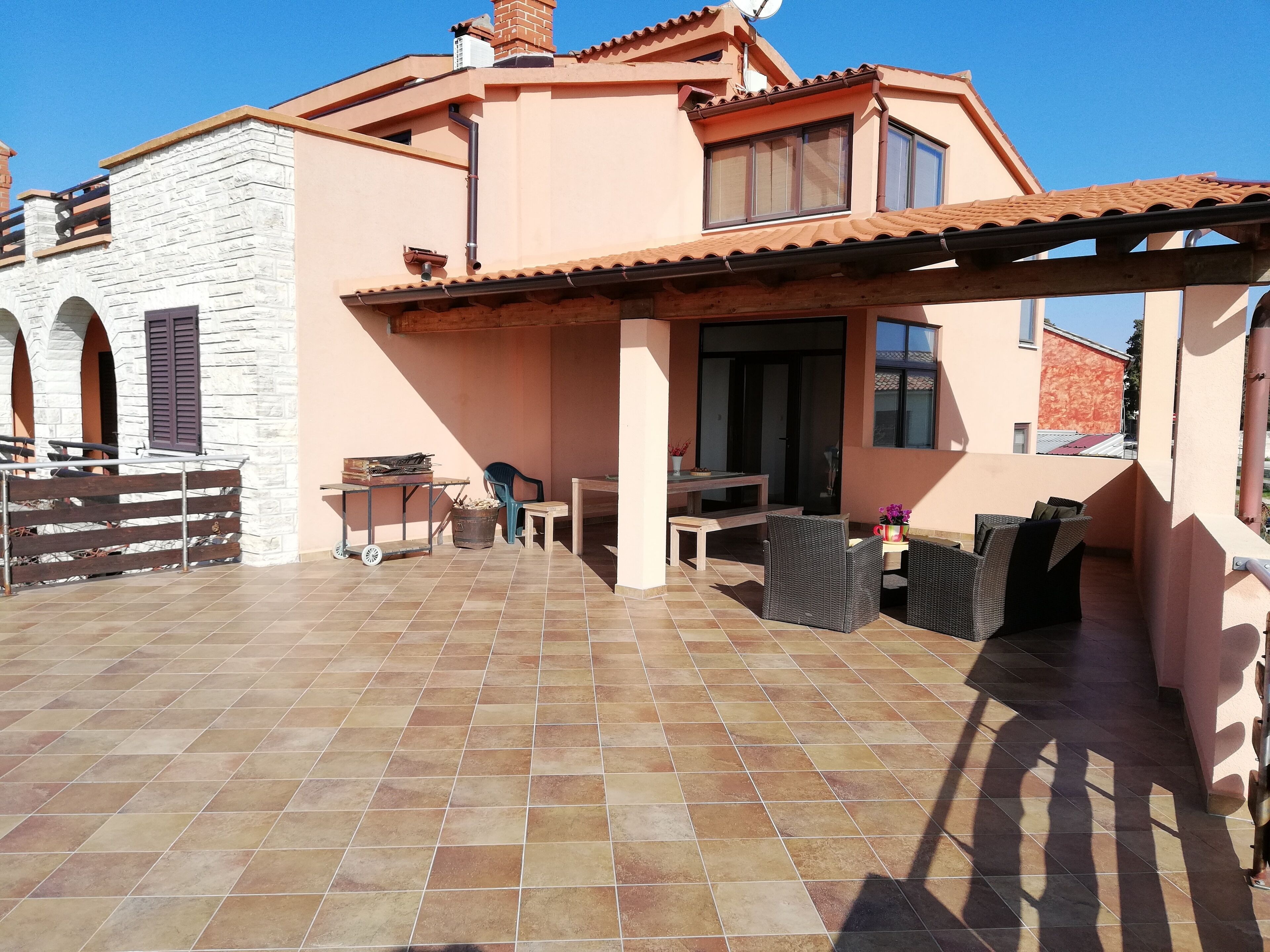 A house with a patio area featuring a table, chairs, and a small table with items on it.