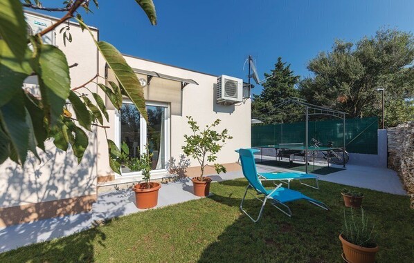 A modern outdoor patio with a blue chair, potted plants, and a bicycle.