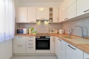 A modern kitchen with white cabinets, a microwave, a kettle, and a sink. - Apartment 1807 (Pula)
