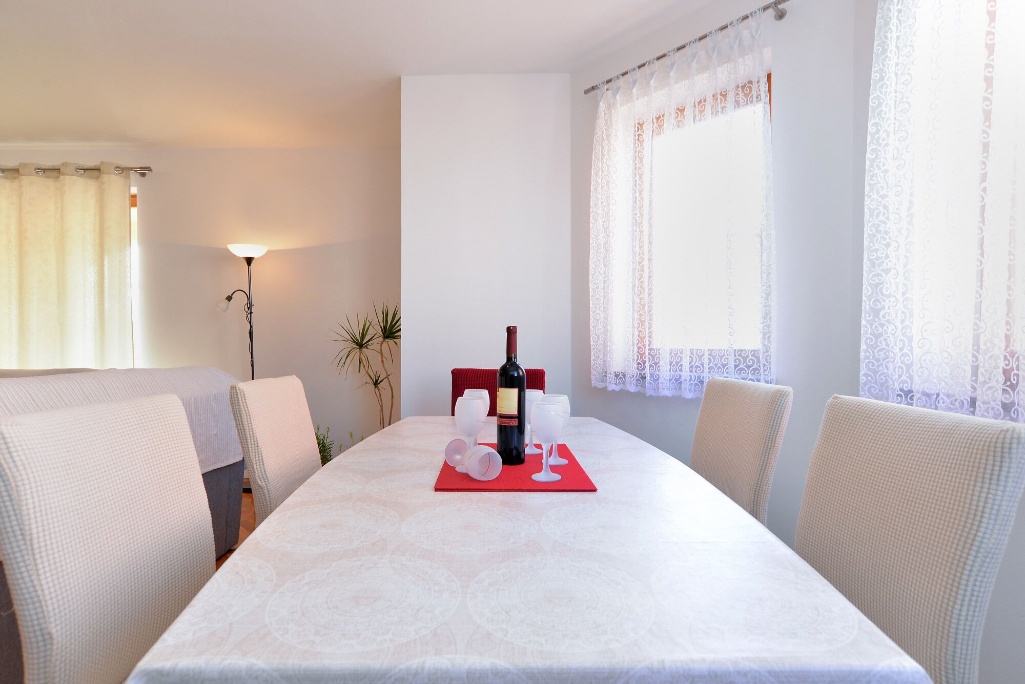 Een eethoek met een tafel voor twee, een fles wijn en een rode placemat.