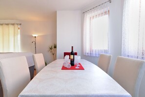Een eethoek met een tafel voor twee, een fles wijn en een rode placemat.