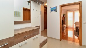 Un apartamento moderno con tocador de madera, un pequeño rincón de cocina y una sala de estar con sofá y cortinas.