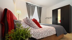 Ein modernes Schlafzimmer mit einem Bett, einem Nachttisch mit Lampe, einer Zimmerpflanze und einem Kleiderschrank.