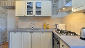 A kitchen with white cabinets, a gas stove, a microwave, and a sink. - Apartment 1814 (Kanfanar)