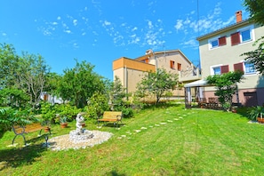 Ein gepflegter Garten mit einem Brunnen, Bänken und einer kleinen Statue.