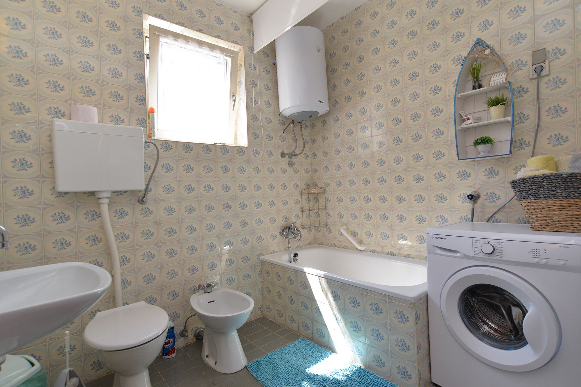 A bathroom with a toilet, bidet, bathtub, and washing machine.