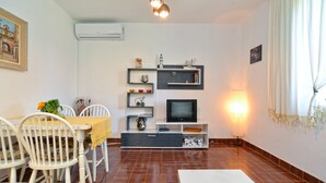 A living room with a TV, shelves, and a dining area with chairs. - Apartment 1817 (Fazana)
