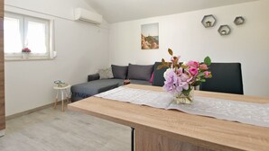 Un salon moderne avec un canapé, une petite table, un vase de fleurs et un tableau accroché au mur.