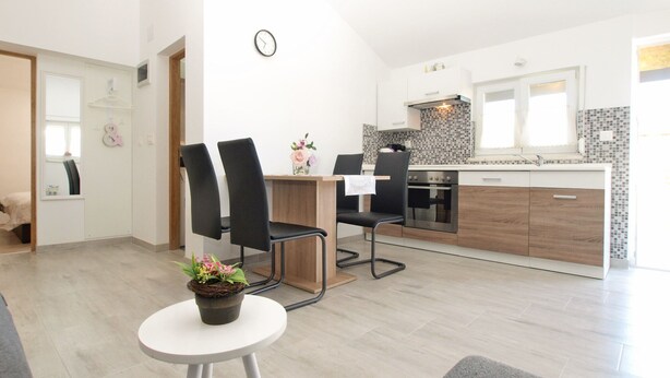 Une cuisine moderne avec deux chaises noires, une table à manger et une petite plante en pot.