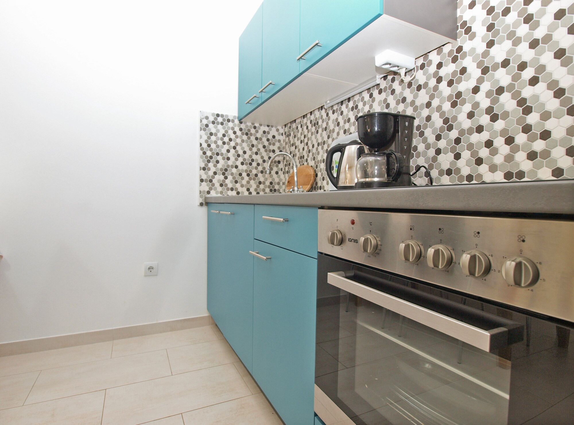 Een keuken met turquoise kastjes, een roestvrijstalen oven en een betegelde achterwand.