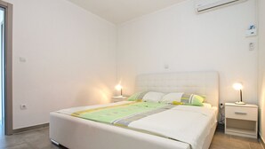 Een keurig opgemaakt slaapkamer met een groot bed, twee nachtkastjes met lampen en een wandairconditioner.