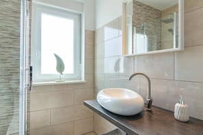 A modern bathroom with a large window, a vessel sink, and a mirror.