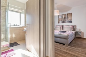 A modern bedroom with a bed, bedside tables, and a window.