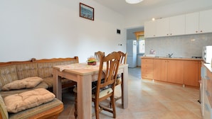 A cozy dining area with a wooden table and chairs, a sofa with cushions, and a kitchen with cabinets and appliances. - Apartment 1822 (Pula)