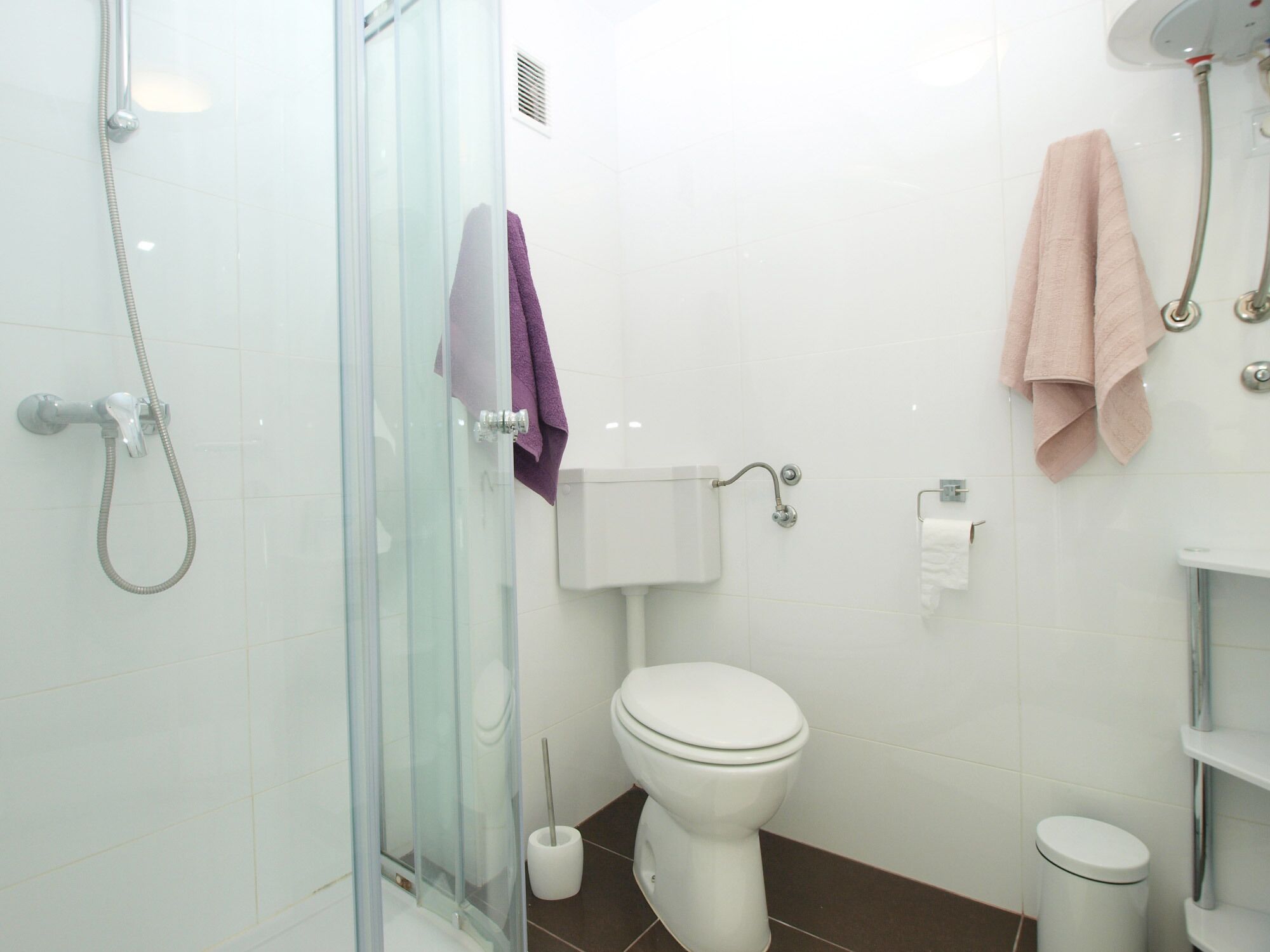 Ein Badezimmer mit Duschkabine aus Glas, Toilette, Bidet und Mülleimer.