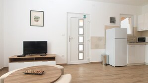 Eine moderne Küche mit weißen Schränken, einer Mikrowelle und einem Kühlschrank. Es gibt einen Essbereich mit einem Holztisch und Stühlen.