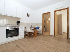 Eine moderne Küche mit weißen Schränken, einem eingebauten Backofen und einem Essbereich mit Tisch und Stühlen.