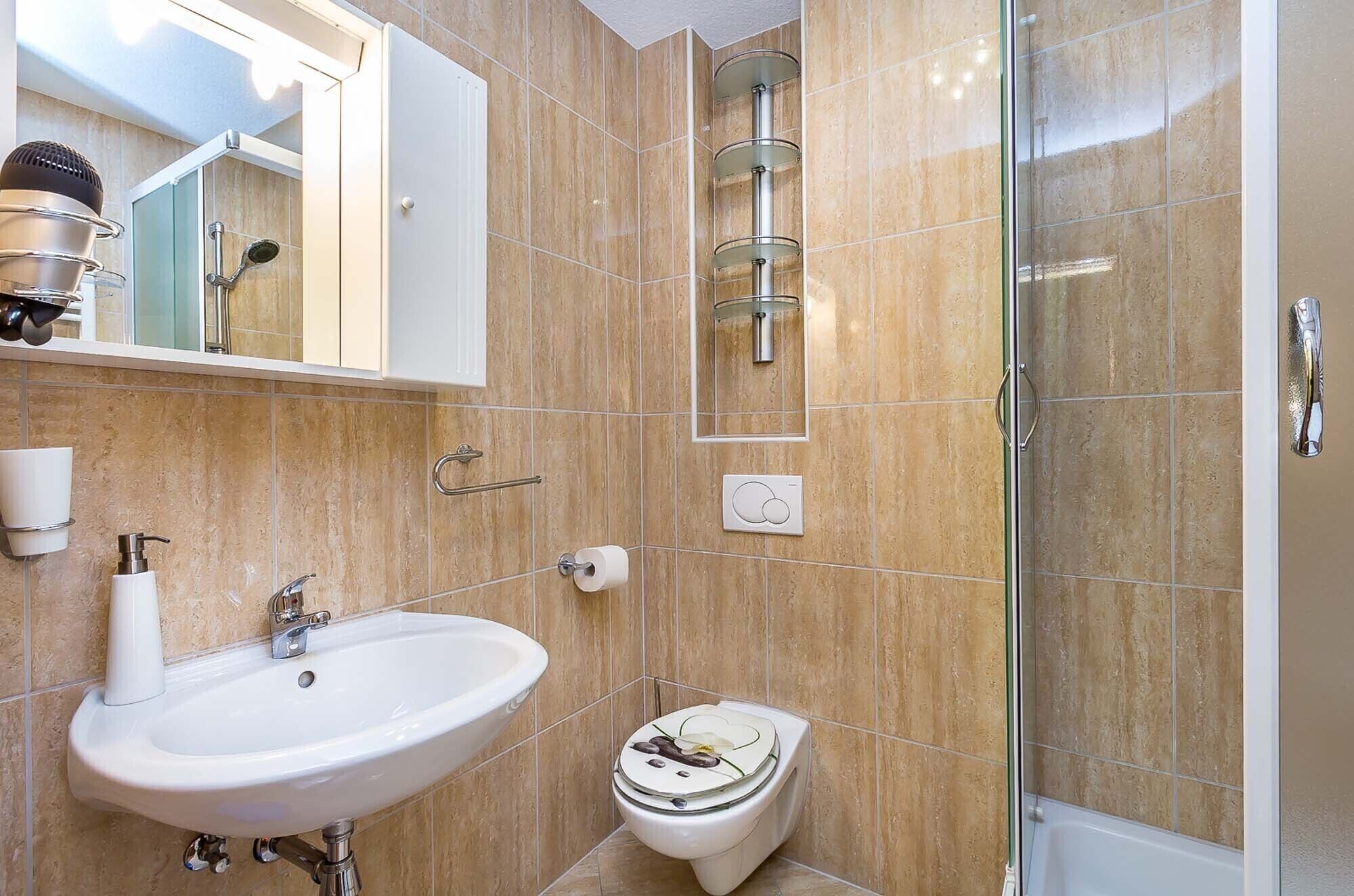 A bathroom with a white sink, a toilet, and a glass-enclosed shower area.