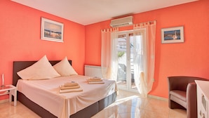 Une chambre d’hôtel avec un lit, une chaise, une table et une fenêtre avec des rideaux.
