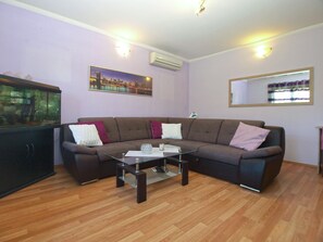 A living room with a brown sofa, a glass coffee table, and a cityscape painting on the wall. - Apartment 1844 (Pula)