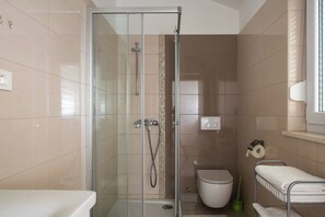 Un baño moderno con ducha de vidrio, inodoro y perchero para toallas.