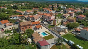 An aerial view of a residential area with houses, a church, and a swimming pool. - House 1855 (Liznjan)