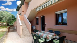 An outdoor patio with a table and chairs, a staircase, and a building with a door and windows. - Apartment 1858 (Fazana)