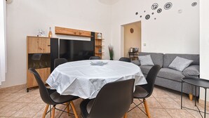 A dining area with a round table, chairs, and a wooden cabinet. - Apartment 1858 (Fazana)