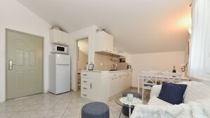A compact living space with a kitchenette, a dining area, and a seating area with a sofa and ottoman. - Apartment 1860 (Medulin)