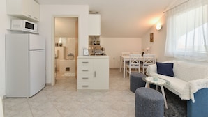 A compact living space with a kitchenette, a dining area, and a seating area with a sofa and ottoman. - Apartment 1860 (Medulin)