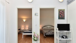 A hotel room with a bed, bedside table, lamp, and a TV on a stand. - Apartment 1860 (Medulin)