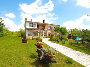A two-story house with a stone facade, a balcony, and a paved pathway leading to the entrance. - Apartment 1862 (Zminj)