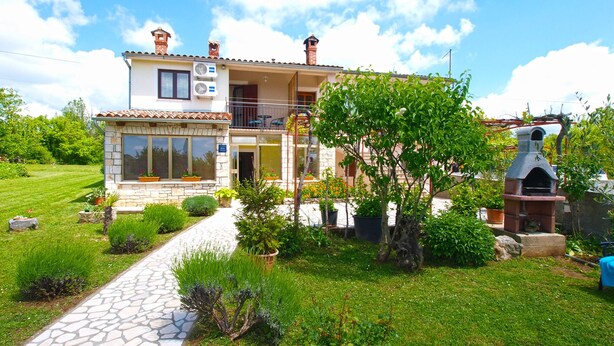 A two-story house with a stone facade, a balcony, and a garden with a stone pathway. - Apartment 1862 (Zminj)
