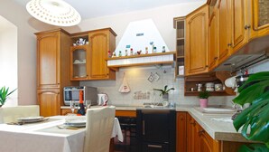 Een keuken met houten kastjes, een eettafel gedekt voor twee personen en diverse keukenapparaten.