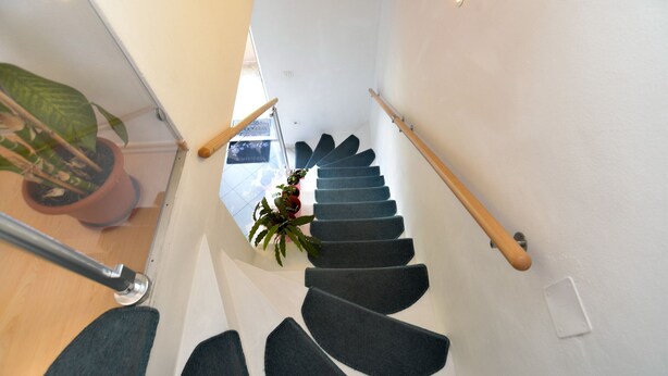 A modern staircase with dark carpeted steps and wooden handrails, leading to an upper floor. - Apartment 1873 (Pula)